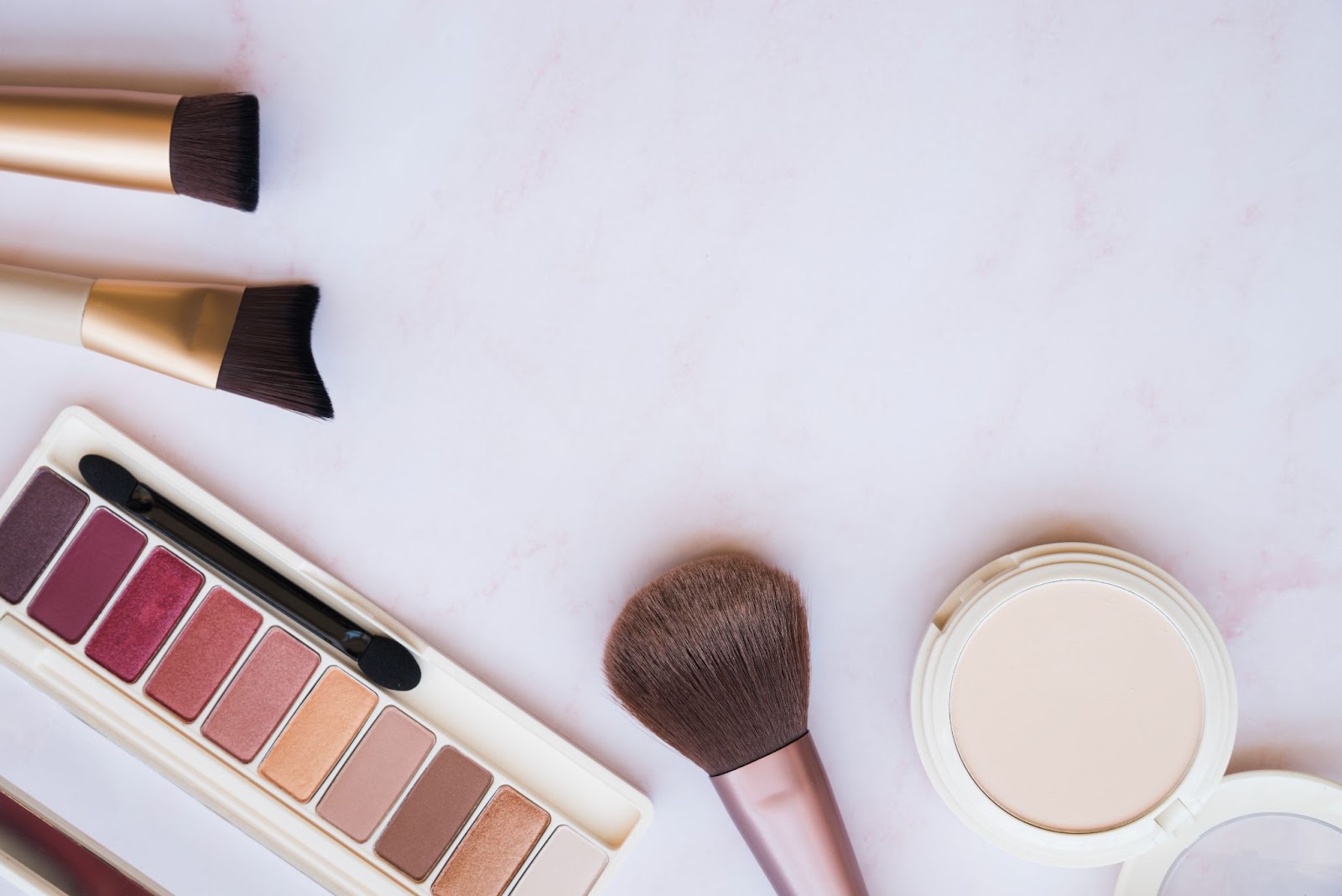 a group of makeup brushes and a palette of eyeshadow